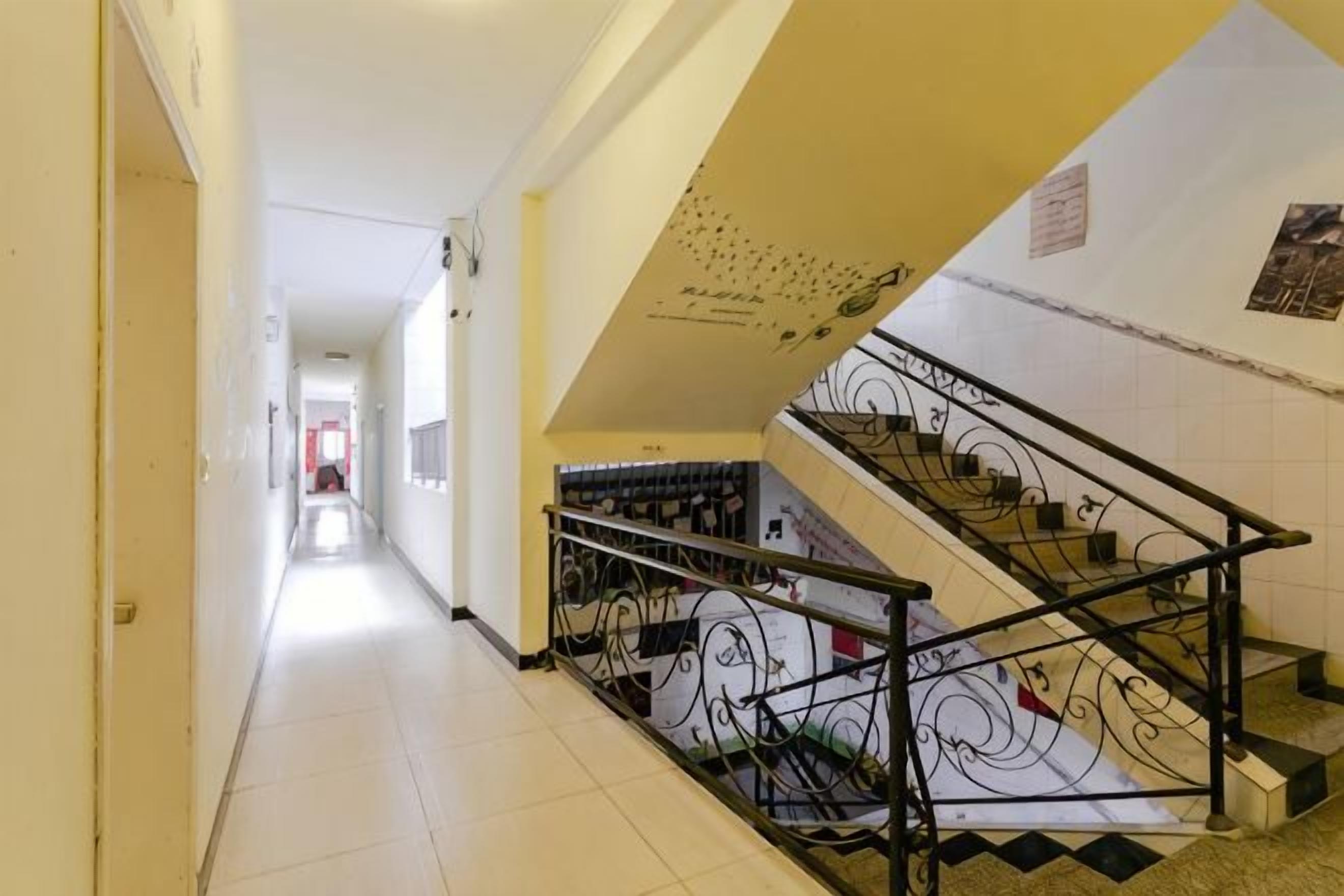 Un pasillo con una escalera, una puerta al final y un cartel en la pared.
