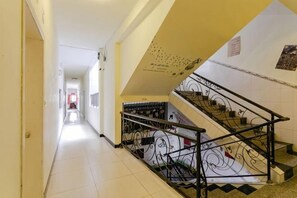 Un pasillo con una escalera, una puerta al final y un cartel en la pared.