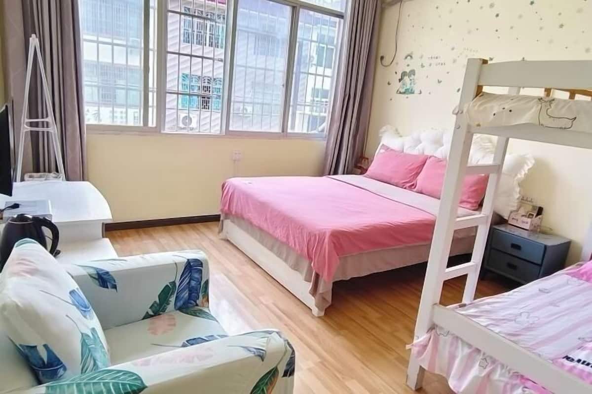 Un dormitorio con una cama litera, un sofá, un escritorio y una ventana con cortinas.