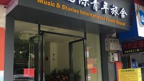 Music & Stories International Youth Hostel -nuorisomajatalon sisäänkäynti, jossa on lasiovet ja sen yläpuolella kyltti.