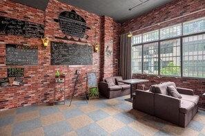 Una habitación con pared de ladrillo, un ventanal grande, un sofá y una mesa.