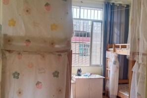 A room with a bunk bed, a desk with a kettle, and a window with bars. - Music & Stories Youth Hostel (Libo)