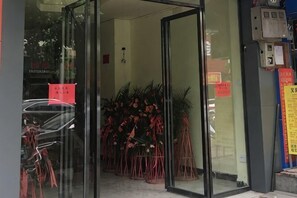 A hotel entrance with glass doors, potted plants, and a visible sign on the wall. - Music & Stories Youth Hostel (Libo)