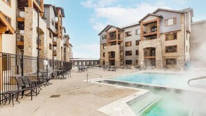 Un hotel con zona de piscina, mobiliario de exterior y varios balcones.