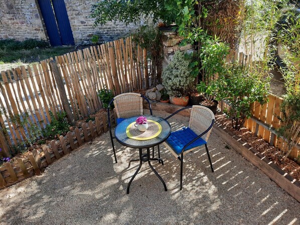 An outdoor patio with two wicker chairs and a round table, surrounded by a wooden fence and various potted plants. - Steredeg - BADEN - Gîte (BADEN)
