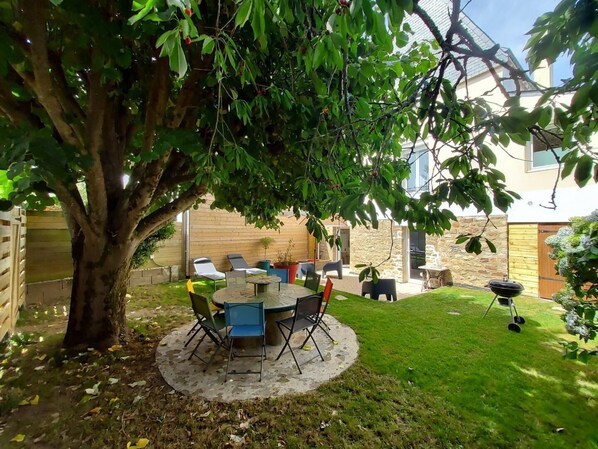 Relax in a serene outdoor space surrounded by lush greenery and a shaded seating area.