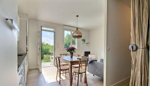 Una cocina moderna con armarios de madera, una mesa de comedor con sillas y un lámpara colgante.