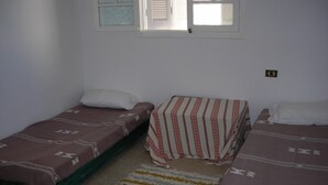 A room with two single beds, a window with blinds, and a small wall-mounted light switch. - Charming house in a beautiful Monastirienne city (Monastir)