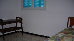 A bedroom with a bed, a wooden desk, and a window with blue shutters. - Charming house in a beautiful Monastirienne city (Monastir)