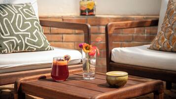 Una mesa de madera con un vaso de bebida roja, un jarrón transparente con flores y un cuenco de cerámica.