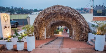 A rustic, woven archway leading to a building with a sign reading "The Nest".