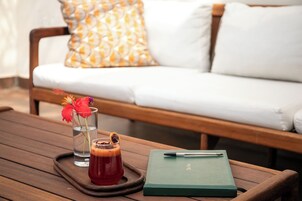 Una mesa de madera con una bandeja que sostiene un vaso de té helado, una libreta y un bolígrafo.