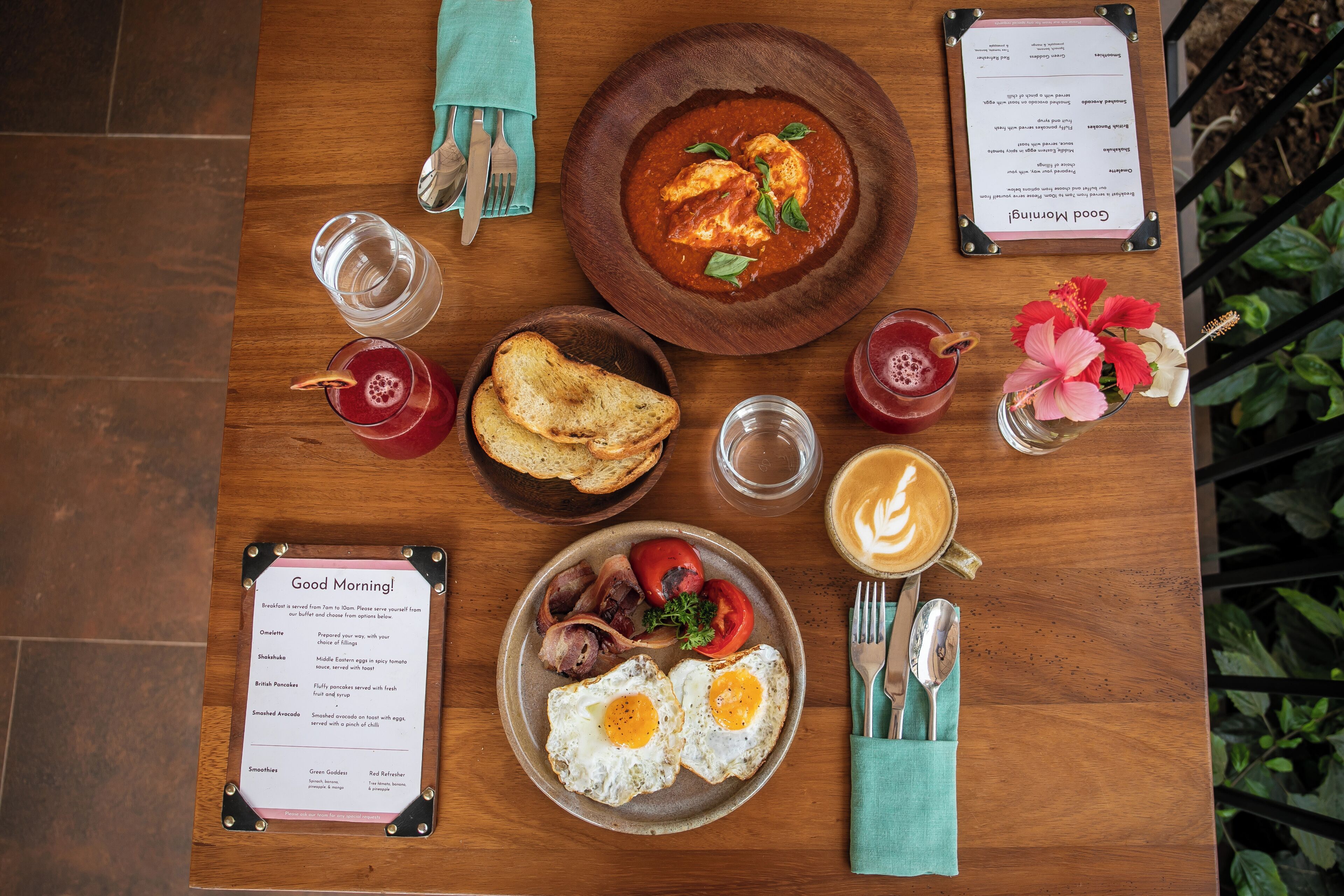 A breakfast table with a menu, toast, eggs, tomatoes, and a coffee cup.