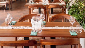 Un restaurante con mesas y sillas de madera, algunas con servilletas verdes y copas de vino.