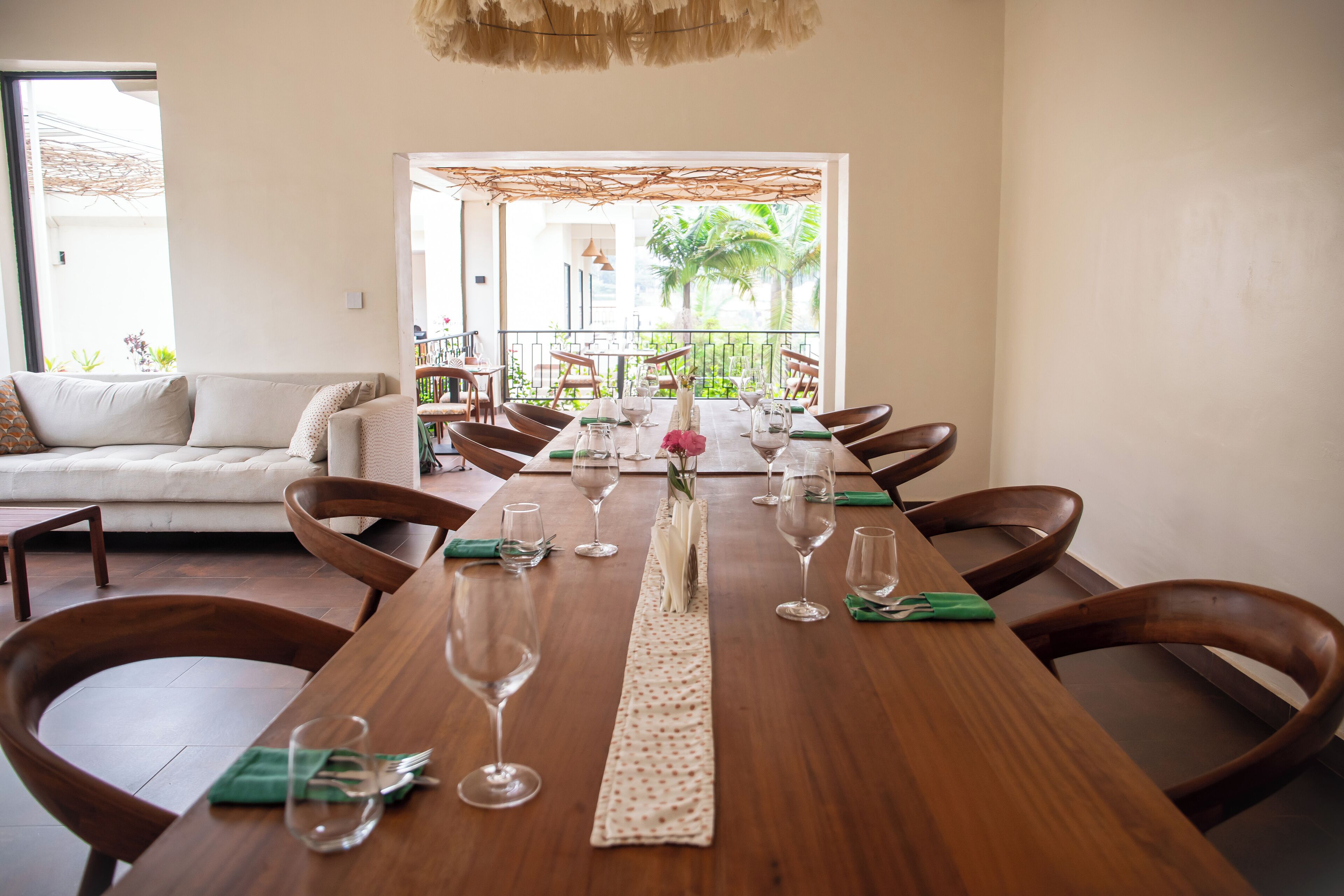 A dining area with a long wooden table set for six, surrounded by wooden chairs.