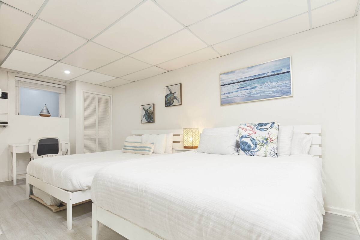 A bedroom with two beds, a desk, and a window with shutters.