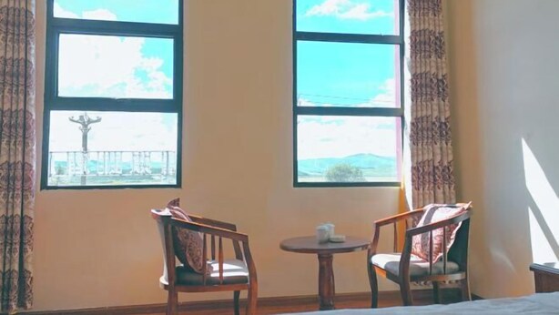 A room with two windows, a bed, two chairs, and a small table.