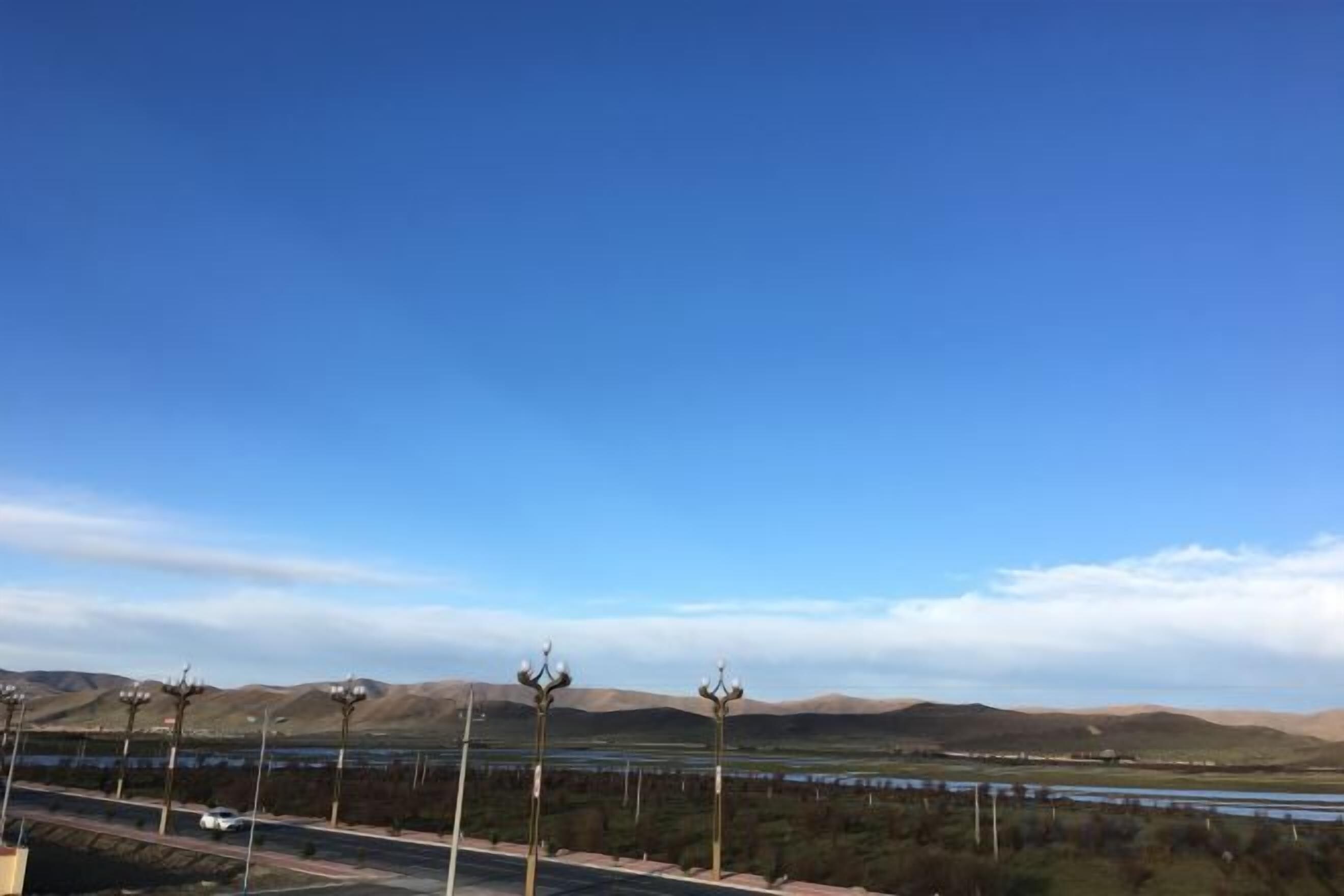 Un cielo azul despejado sobre un puente con colinas a lo lejos.