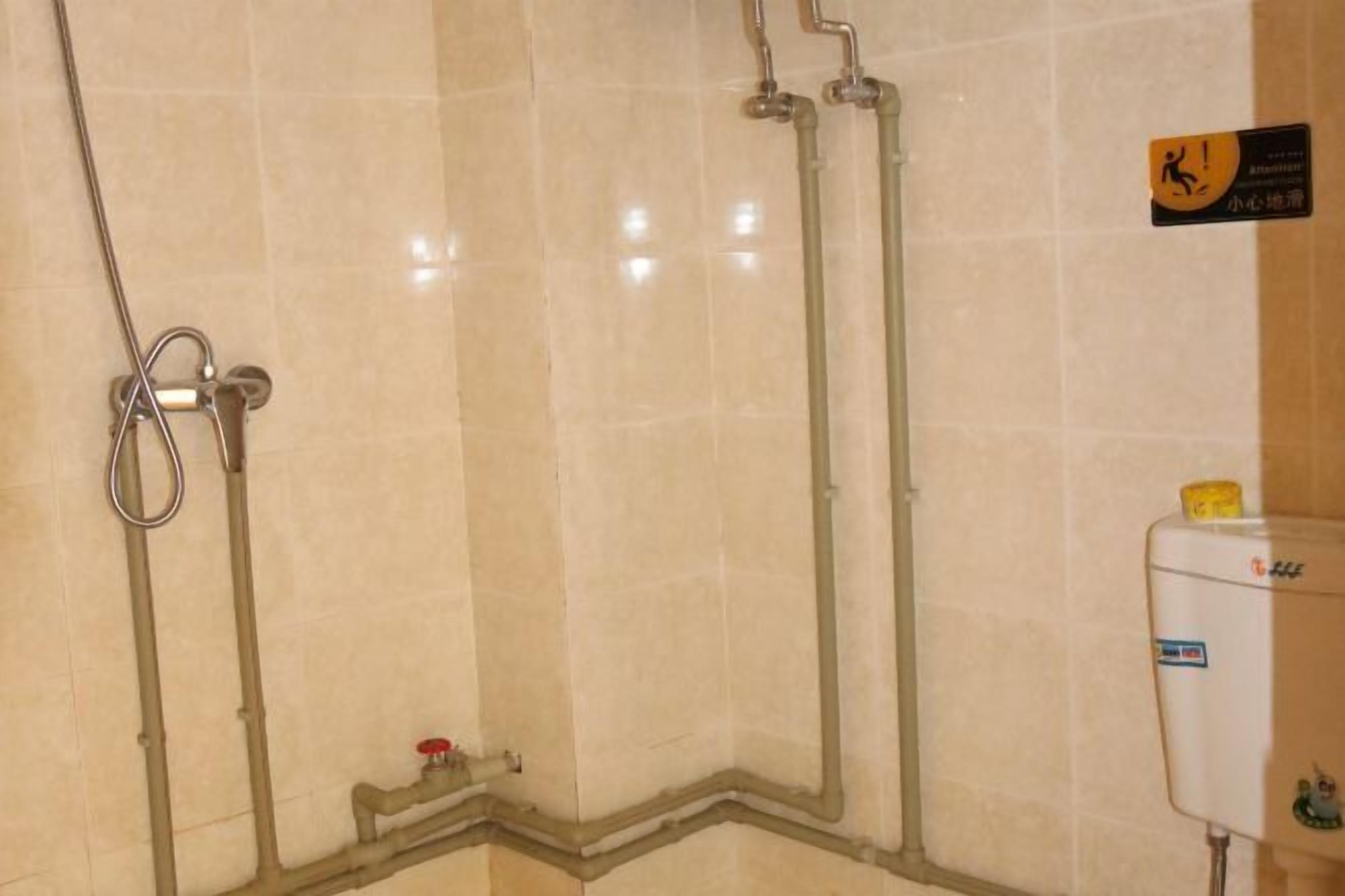 A shower area with tiled walls, a showerhead, and a water heater.