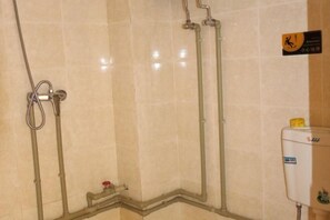 Douchegedeelte met betegelde wanden, een douchekop en een boiler.