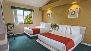 Ett hotellrum med två sängar, ett fönster med utsikt över träd och en stol.