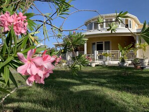 Une maison à deux étages dotée d’un porche abrité, entourée d’une pelouse bien entretenue et de plantes en pot.
