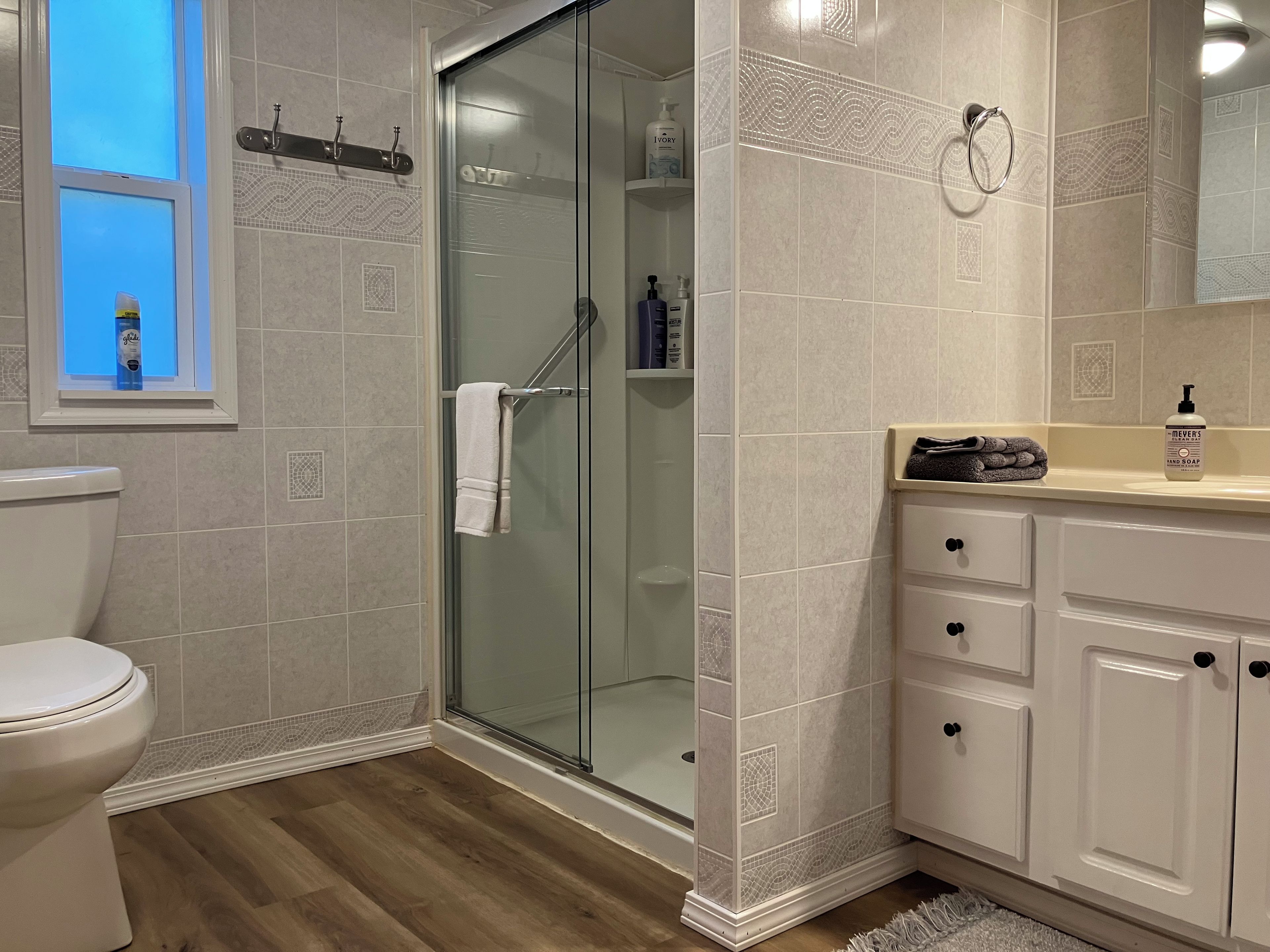 A bathroom with a glass-enclosed shower, a toilet, and a vanity with drawers.