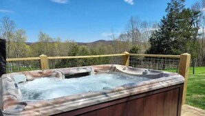 A hot tub with a wooden deck and a bench.
