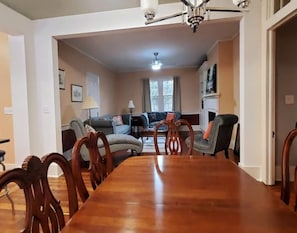 A dining area with a wooden table and chairs, a sofa set, and a fireplace.