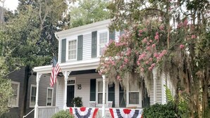 Uma casa de dois andares com varanda, número 18, e uma bandeira americana.