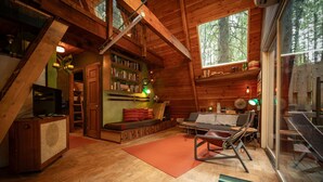 L’intérieur chaleureux d’un chalet, avec un revêtement mural en bois, une bibliothèque, un canapé et un téléviseur.