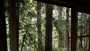 Un bain à remous situé dans un espace boisé, avec des murs en pierre et une terrasse en bois.