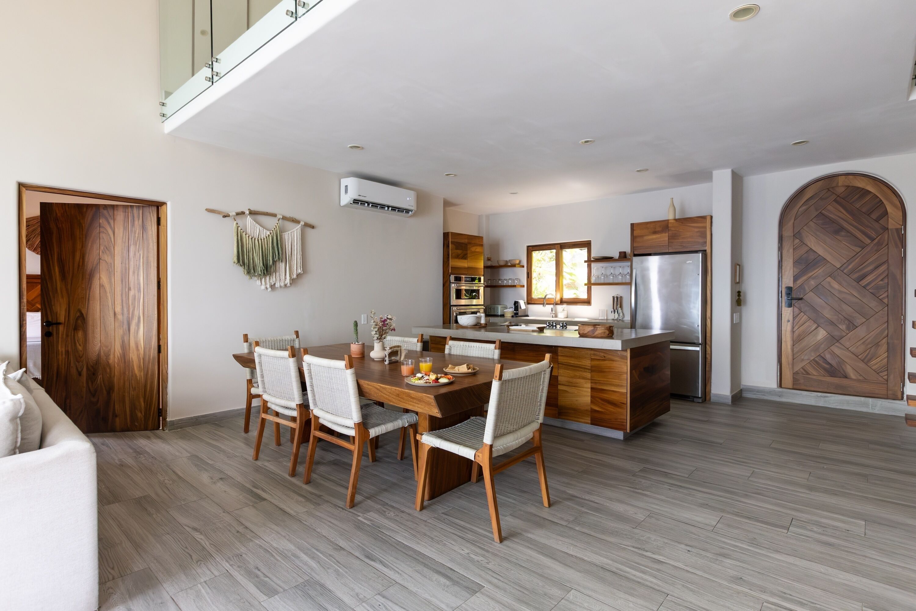 Una cocina moderna con horno empotrado, refrigerador y puerta de madera.