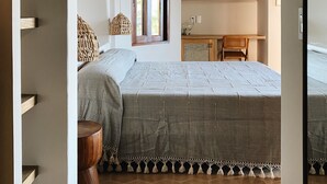 A bedroom with a thatched ceiling, a bed, a desk, and a window. - La Joya Sayulita (Sayulita)