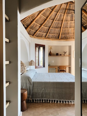 A bedroom with a thatched ceiling, a bed, a desk, and a window. - La Joya Sayulita (Sayulita)
