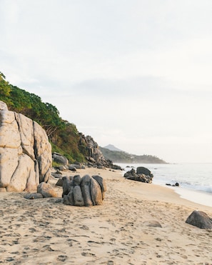 A beach with large rocks, a sandy shore, and a mountain in the background. - La Joya Sayulita (Sayulita)