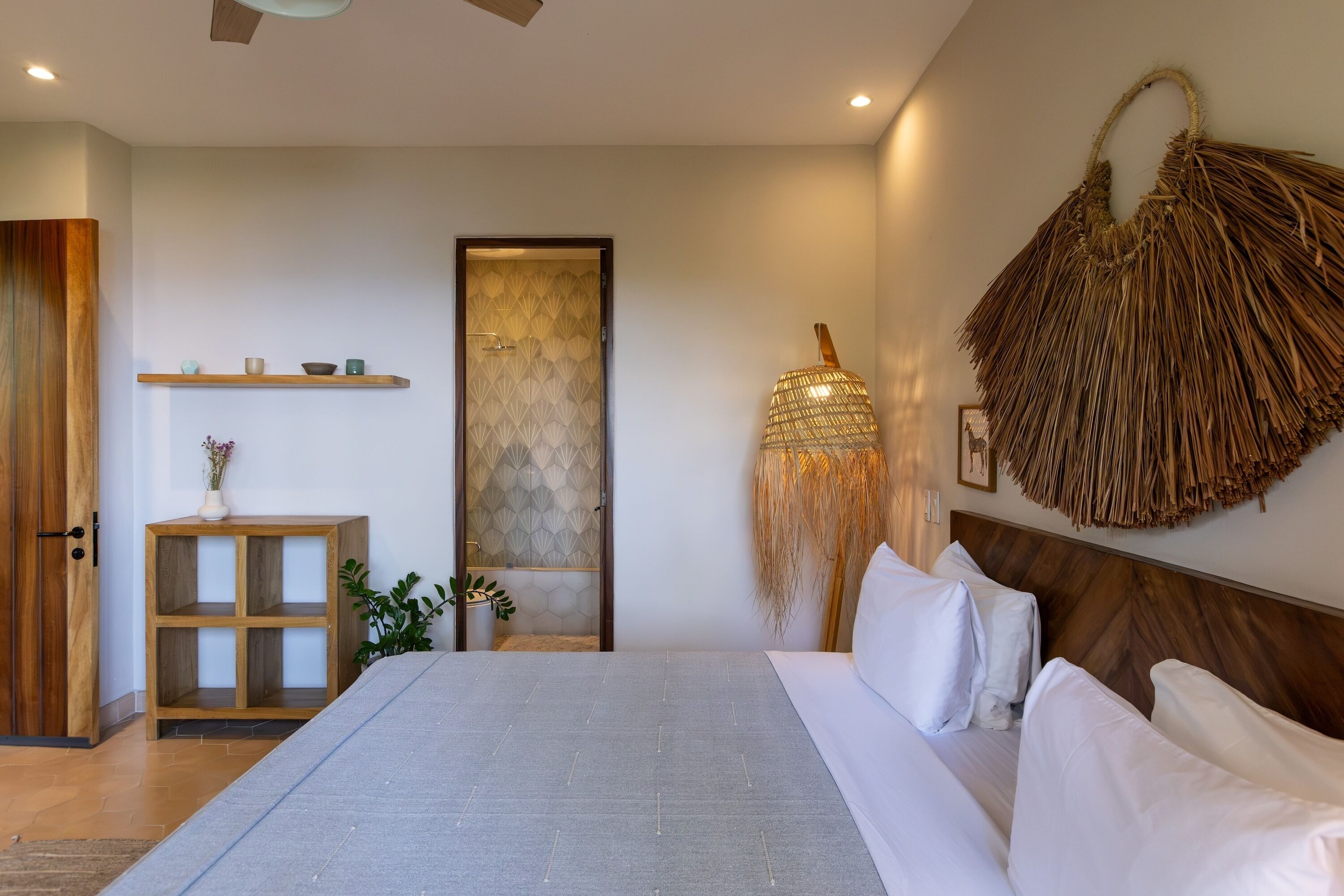 Un dormitorio moderno con una cama grande, una mesita de noche de madera, un estante montado en la pared y una lámpara de techo tejida original.