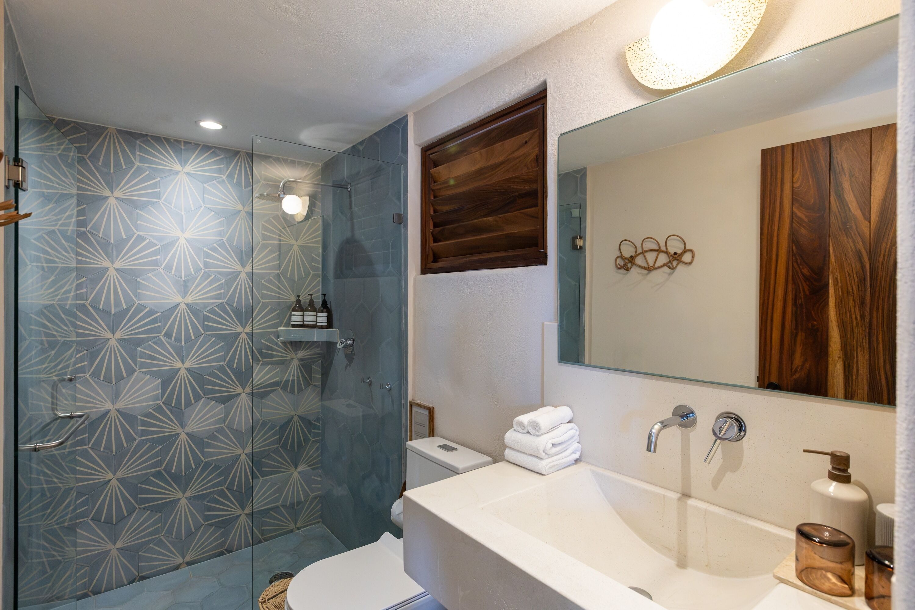 A modern bathroom with a glass shower enclosure, a white sink, and a large mirror.