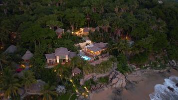 Un resort con varias construcciones rodeado de exuberante vegetación tropical y una playa.