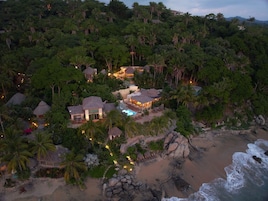 Un resort con varias construcciones rodeado de exuberante vegetación tropical y una playa.