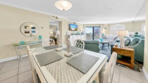Sala de estar moderna com área de jantar, televisão e vista da cidade.