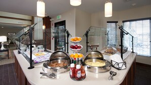 Un comptoir de buffet proposant divers plats, des bouteilles de condiments et une vitrine réfrigérée.