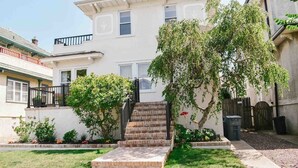 A two-story residential building with a front yard, a staircase leading to the entrance, and a small garden area. - Private 2nd story apartment in the heart of Long Beach- Pura Vida! (Long Beach)