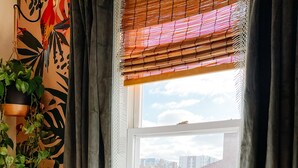 A bedroom with a bed, a window with a view of buildings, and a plant. - Private 2nd story apartment in the heart of Long Beach- Pura Vida! (Long Beach)