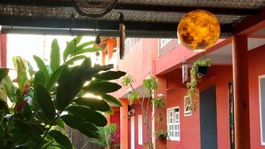 Une cour avec des murs rouges, des plantes en pot et un luminaire suspendu.
