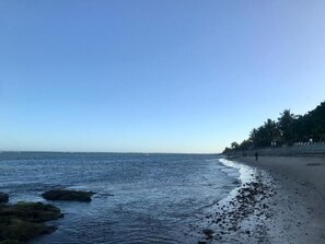 A beach with calm water, a sandy shore, and a line of trees in the background. - Pousada Kawaii (Porto Seguro)