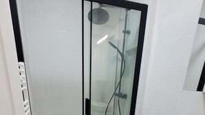 A modern bathroom with a glass-enclosed shower, a white toilet, and a vanity with a sink. - Maisonette Chaleureuse à la Porte de Paris 14 (Gentilly)