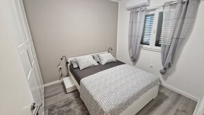 A bedroom with a bed, bedside table, and an air conditioning unit. - NEW Holliday Apartment A2+2, Family house, garden pool, terase, wi-fi (Radonic)