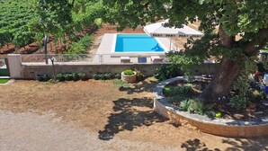 A pool area with a covered seating area labeled "PAN PAN PAN," surrounded by a garden with various plants and a tree. - NEW Holliday Apartment A2+2, Family house, garden pool, terase, wi-fi (Radonic)