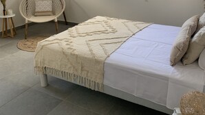 Un dormitorio con cama, ventana, silla y una mesita.